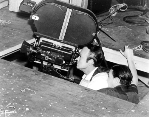 Behind-the-scenes production still: low-angle filming setup on the Citizen Kane set (Orson Welles as director/actor)