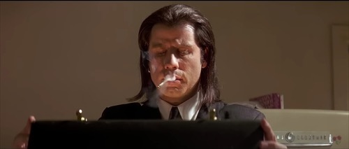 Film still: the briefcase (combination 666) being opened, emitting its golden glow — the canonical Mystery-Box McGuffin